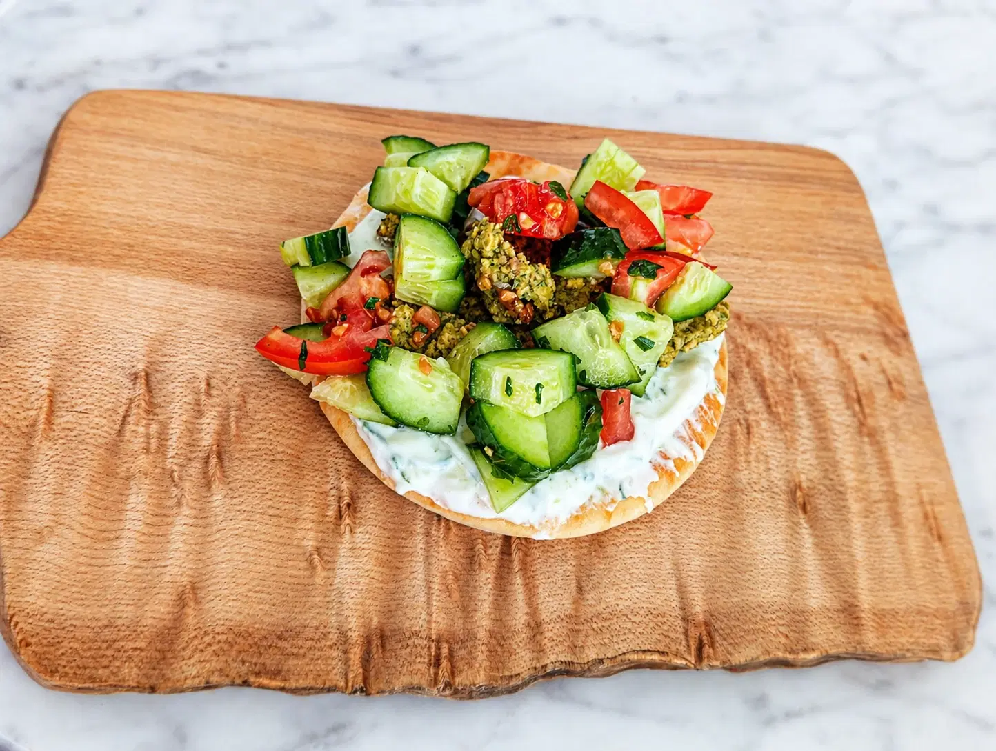 Build-your-own baked falafel pita bar with warm pita, falafel, chopped vegetables, yogurt sauce, and hummus.