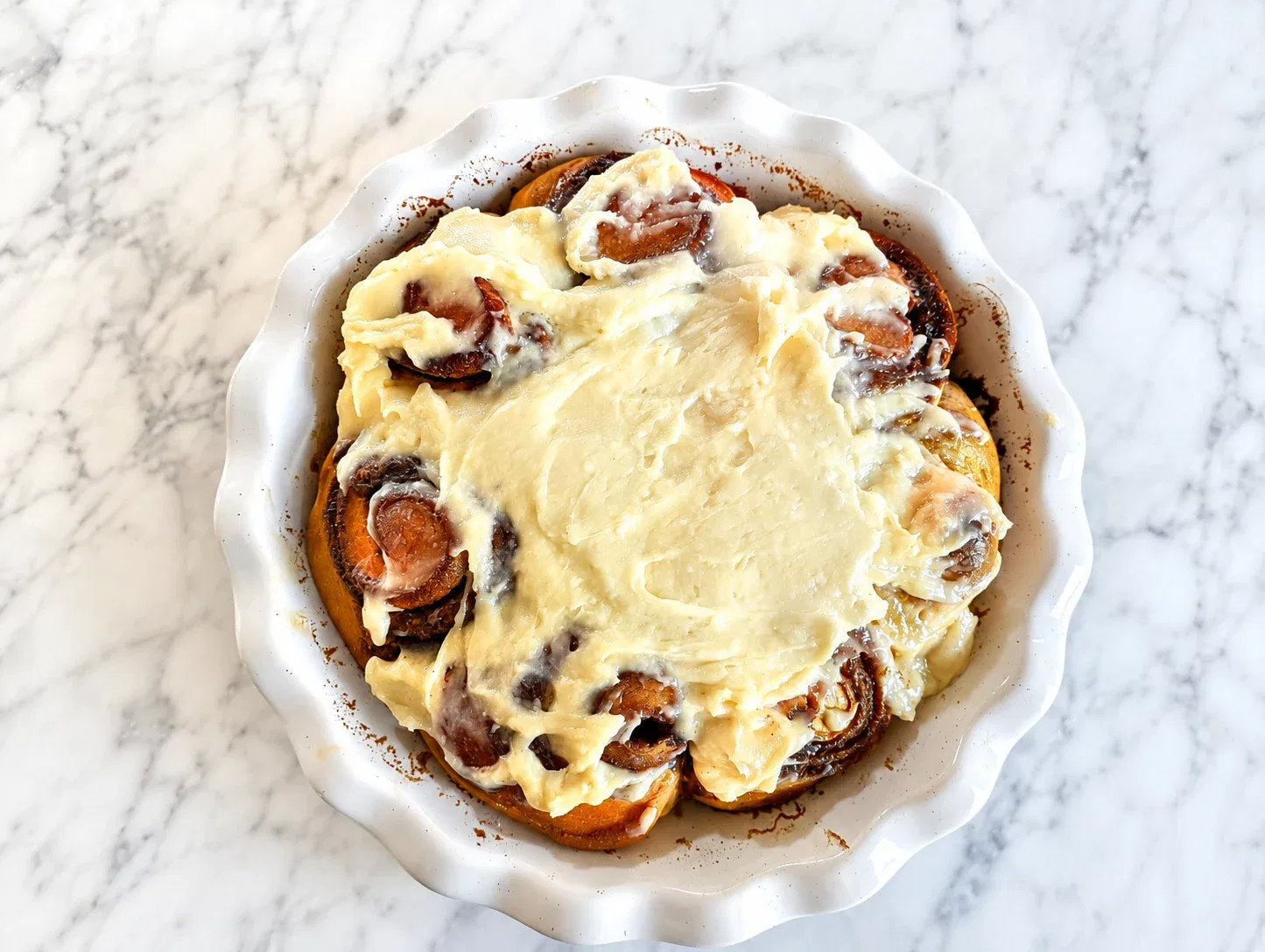 Soft sweet potato sourdough cinnamon rolls with cream cheese frosting in a baking dish